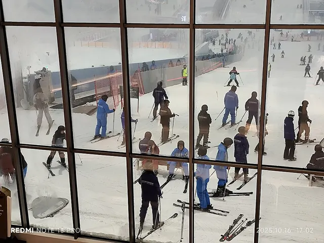 Skiers on the indoor snow slope at Qianhai Huafa Snow World, seen through a viewing window