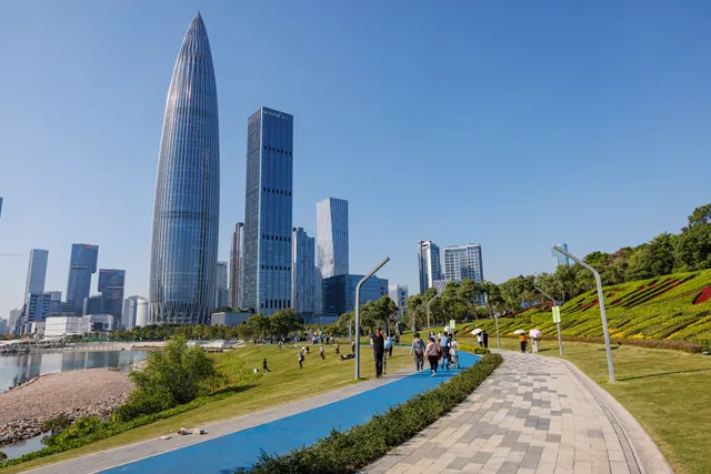 Visitors on the waterfront paths at Talent Park beneath the Shenzhen Bay skyline