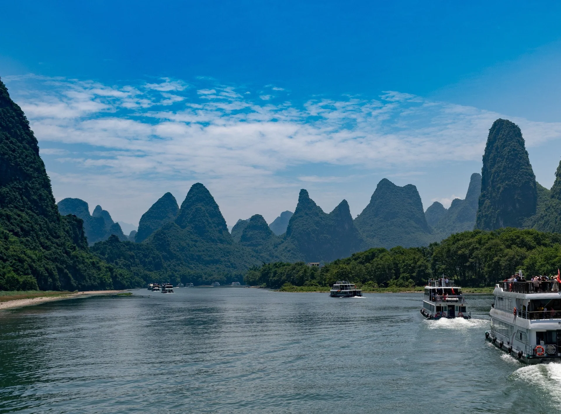Boats travelling between limestone peaks on the Li River in the Guilin region