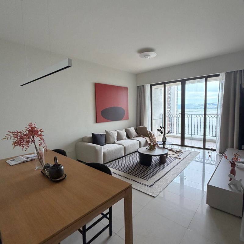 Living and dining room with a sofa and balcony doors in the Coastal Rose Garden Phase III advertiser's gallery