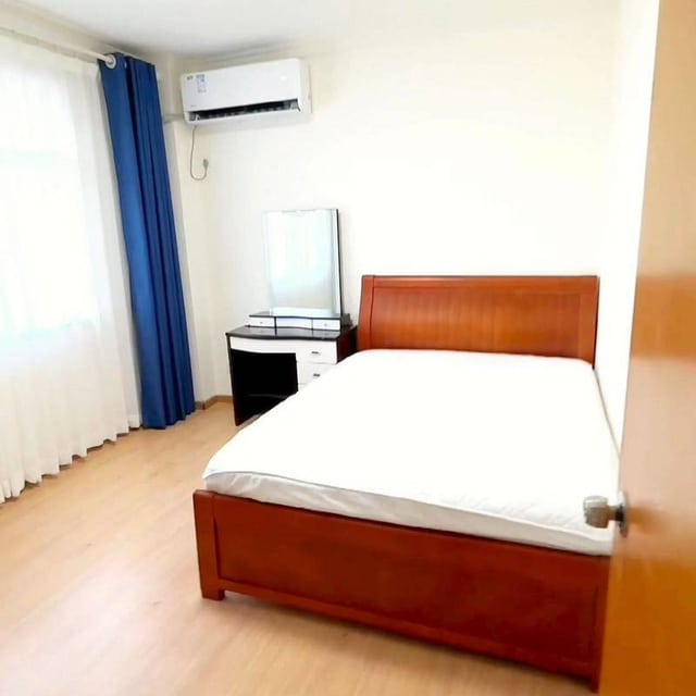 Bedroom with a wooden bed frame, white bedding, blue curtains and a dressing table in the 56 m² Rongcun listing gallery