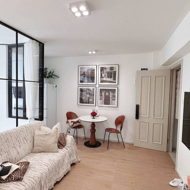 Living room with a cream sofa, round dining table and black-framed glass partition in the 60 m² Rongcun listing gallery